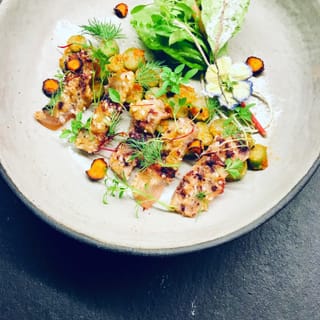Heller Teller mit gebratenem Gemüse, Kräutern und Blüten