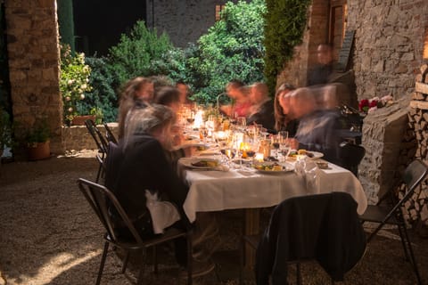 Gäste an einer langen, gedeckten Tafel im Freien, abends bei Kerzenlicht